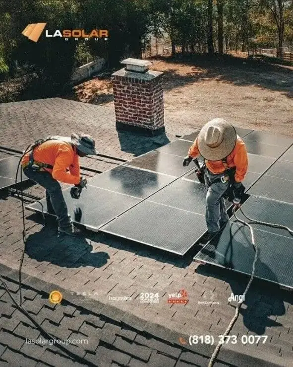 Two workers installing solar panels on a residential roof during roofing service.