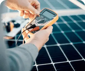 Technician testing solar panel electrical output with multimeter.